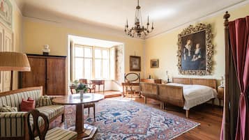 Ein traditionell eingerichteter Raum mit Bett, Schreibtisch, Stuhl, Sofa, Tisch und einer Chandelier.