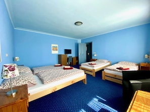 A room with two wooden beds, a desk, a chair, and a wardrobe.