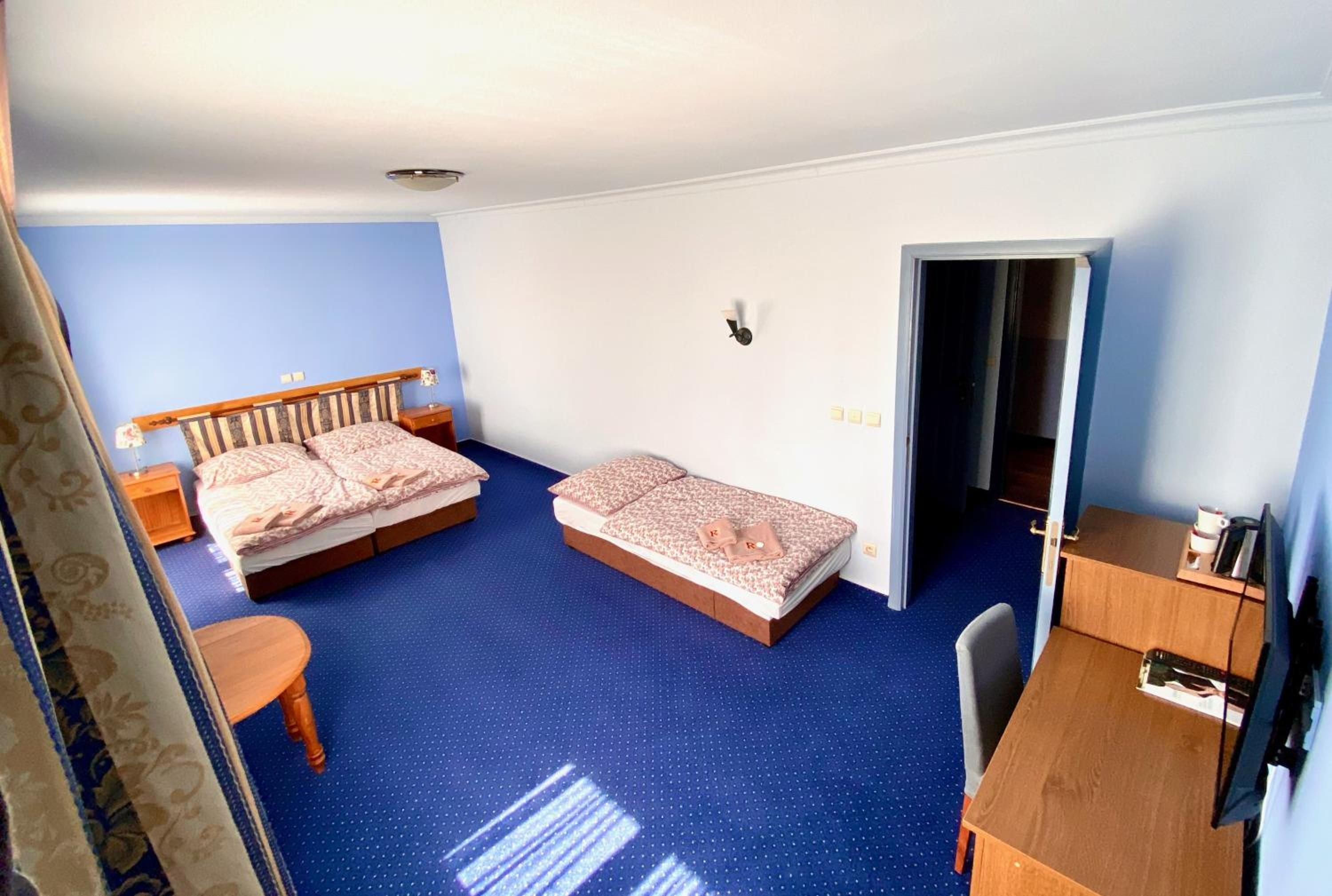 Quarto de hotel com duas camas, uma escrivaninha, uma cadeira e um guarda-roupa.