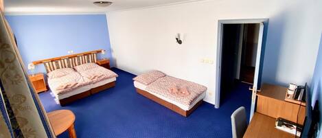 Quarto de hotel com duas camas, uma escrivaninha, uma cadeira e um guarda-roupa.