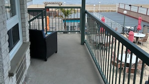 Un balcon avec vue sur la mer, une piscine et un espace salon extérieur.