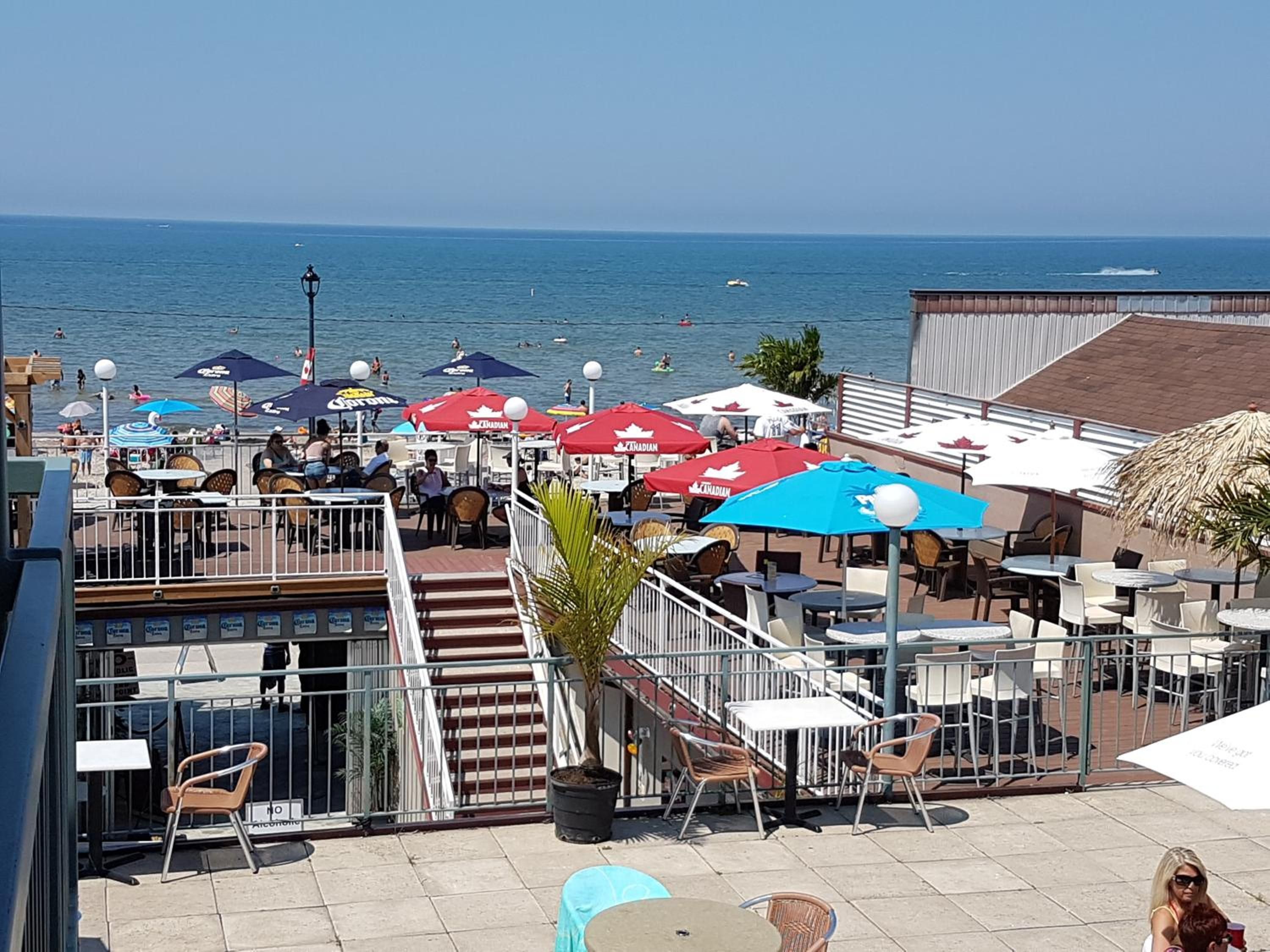 An outdoor seating area with tables and chairs, overlooking a body of water.