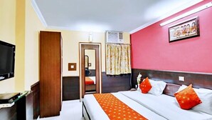 A hotel room with a bed, a television, a desk, and an air conditioning unit. - Hotel Mantri Residency (Ranchi)
