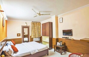 A hotel room with a bed, a television, a wardrobe, a mirror, and a ceiling fan. - Hotel Mantri Residency (Ranchi)