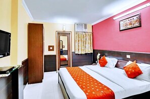 Een hotelkamer met een bed, een televisie, een bureau en een airconditioning.