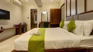 Habitación de hotel con cama, televisión, escritorio y baño visible a través de una puerta abierta.