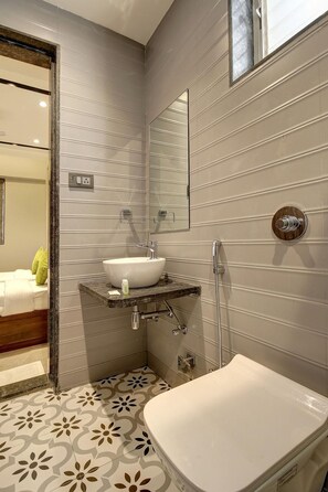 A bathroom with a white bathtub, a sink with a marble countertop, and a mirror above the sink. - Staybird - Fortune House Business Hotel (Pune)