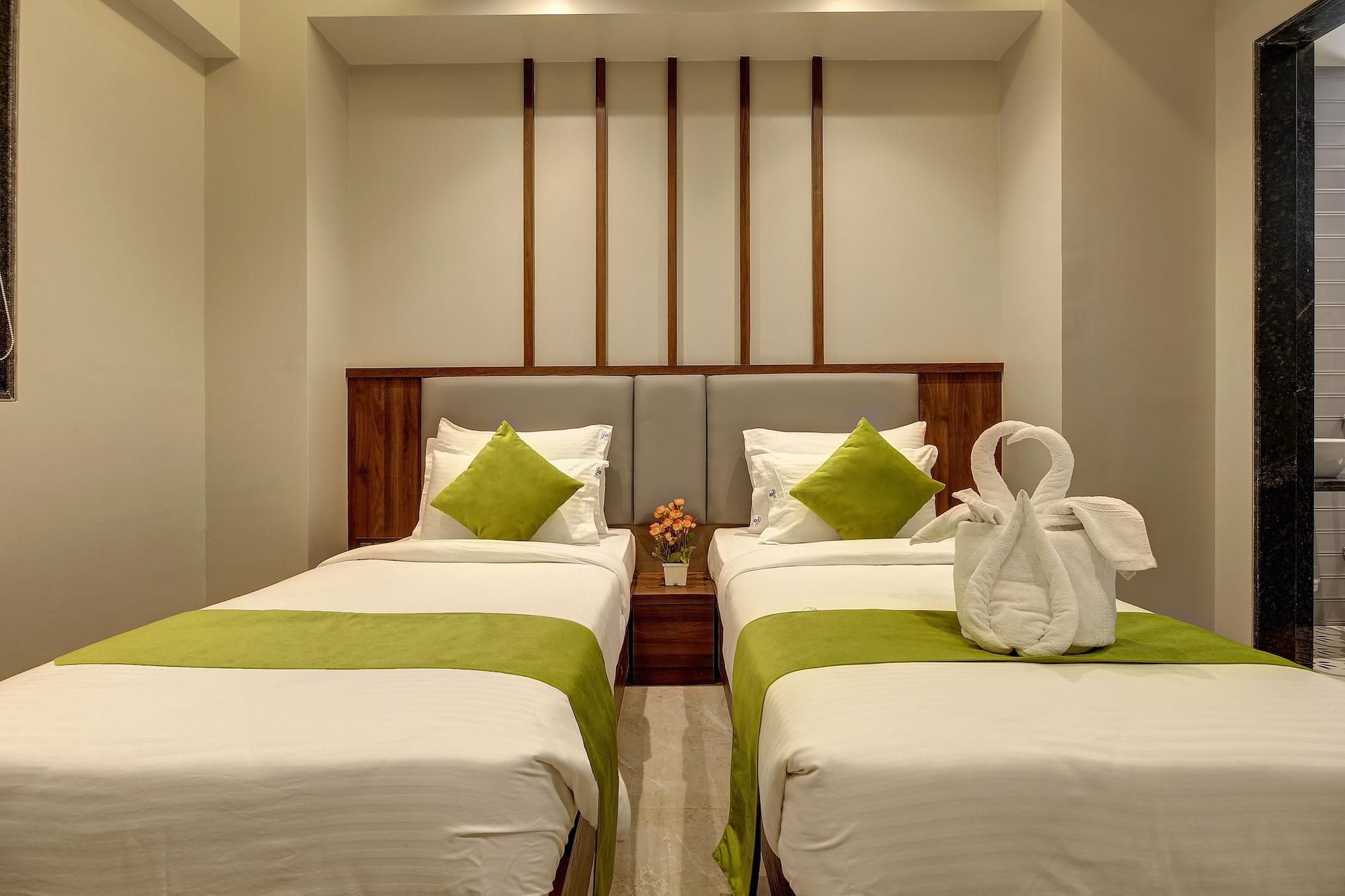 A hotel room with two beds, a wooden headboard, and a towel rack.