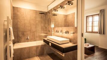 Ein modernes Badezimmer mit einer begehbaren Dusche, einer Badewanne und einem Waschtisch mit großem Spiegel.