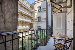 A balcony with a view of a courtyard, a wooden table, and a door. - Vaci Boutique Loft Suites By Bqa (Budapest)