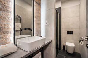 A modern bathroom with a large white sink, a mirror, a shower, and a toilet. - Vaci Boutique Loft Suites By Bqa (Budapest)
