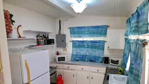 Cuina compacta amb armaris blancs, nevera, microones, fogó de gas i rentaplat.