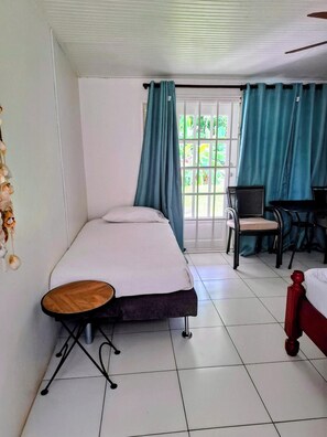 Una habitación con una cama, una mesita, una silla y una ventana con cortinas.