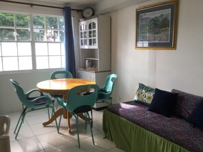 Una habitación con una mesa de comedor y sillas, un sofá, un reloj y un cuadro en la pared.