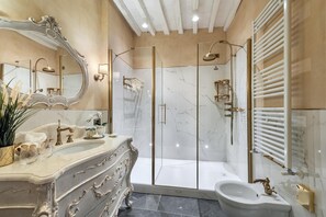 A luxurious bathroom with a marble vanity, a large mirror, a glass-enclosed shower, and a white bathtub. - Il Miraggio In Val D'orcia Relais & Spa (San Quirico d'Orcia)