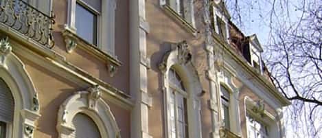 Un edificio de varios pisos con detalles arquitectónicos ornamentales, incluyendo ventanas en arco y molduras decorativas.
