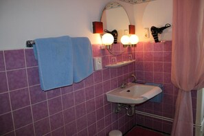 A bathroom with purple tiles, a sink, a mirror, and two towels.