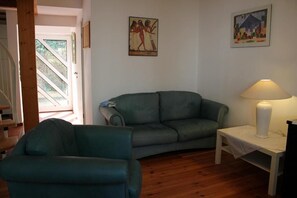 A living room with a sofa, a chair, a lamp, and artwork on the wall.