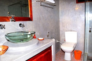 Een badkamer met een wastafel op voet, een wit toilet en een douchehoek.