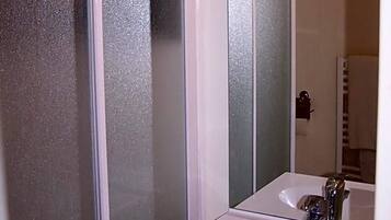 A bathroom with a white sink, a mirror, and frosted glass doors.