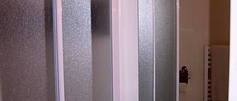 A bathroom with a white sink, a mirror, and frosted glass doors.