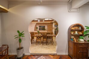 Comedor con pared de ladrillo, mobiliario de madera y vista a otra habitación.