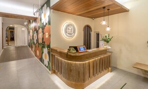 Una recepción con detalles de madera, una pared con un mural floral y un letrero circular con un símbolo de sueño.