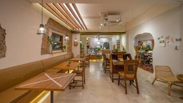 A cozy cafe with wooden furniture, a brick wall, and a view into the kitchen area.