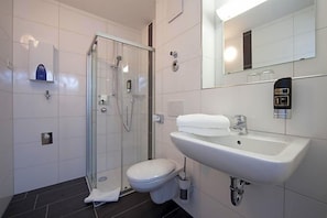 Um banheiro moderno com chuveiro em cabine de vidro, pia branca e vaso sanitário.