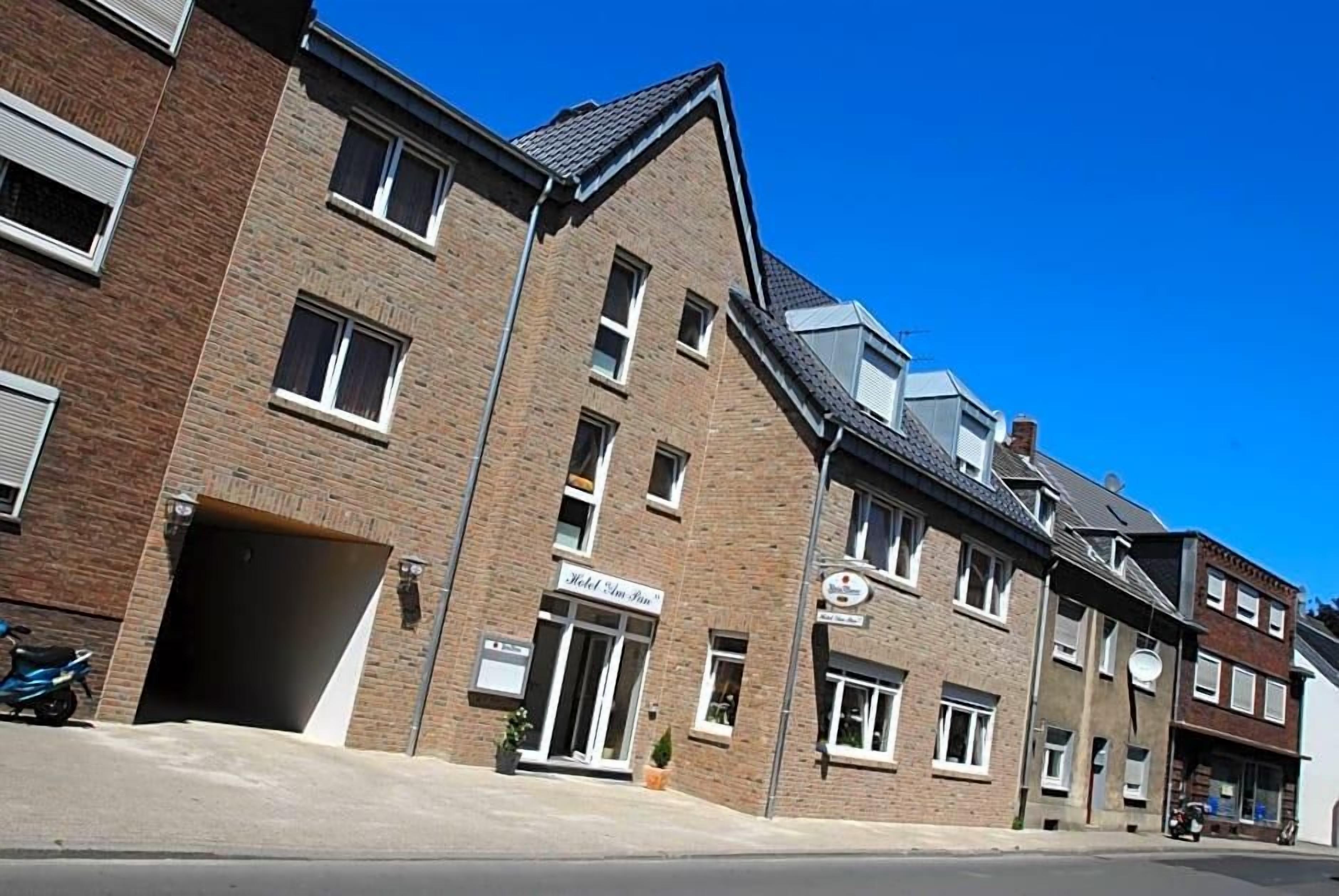 Een meerlaags hotel met een bakstenen gevel, een duidelijke ingang en een helderblauwe lucht.