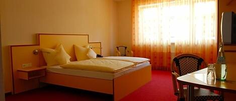 A hotel room with a bed, a chair, a table, and a television.