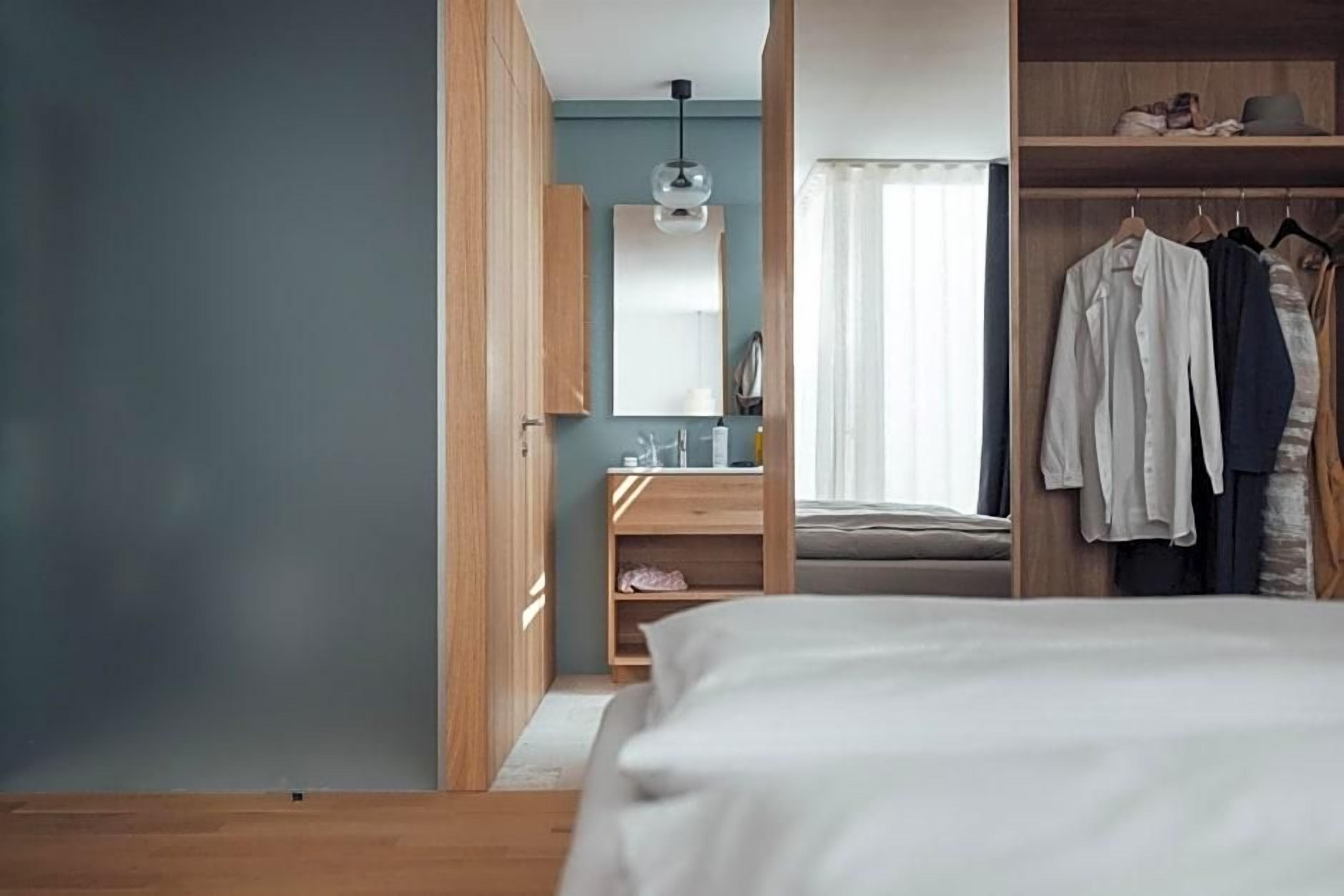 A bedroom with a bed, wooden wardrobe, and a mirror.