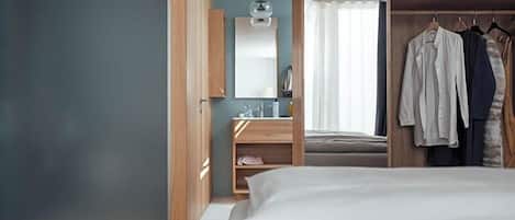 A bedroom with a bed, wooden wardrobe, and a mirror.