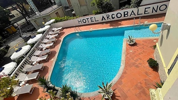 A hotel pool with lounge chairs and a sign reading 'HOTEL ARCOBALENO'. - Hotel Arcobaleno (Celle Ligure)