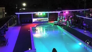 A swimming pool with a stage and seating area, surrounded by a covered deck. - Motel Kratos (Bisignano)