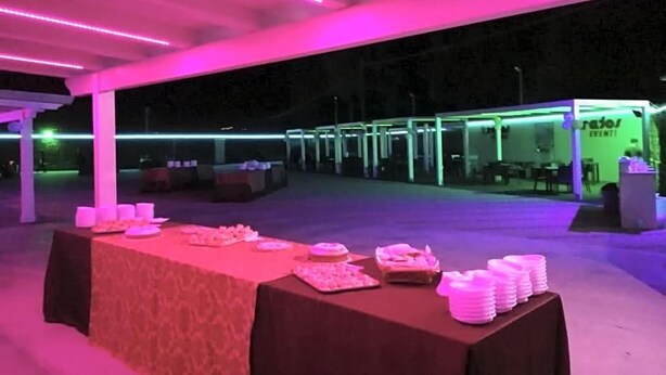 An outdoor event space with tables set up for catering, a tent structure, and a booth with signage. - Motel Kratos (Bisignano)