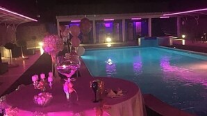 A poolside dining area with a table set for two, surrounded by a pool. - Motel Kratos (Bisignano)
