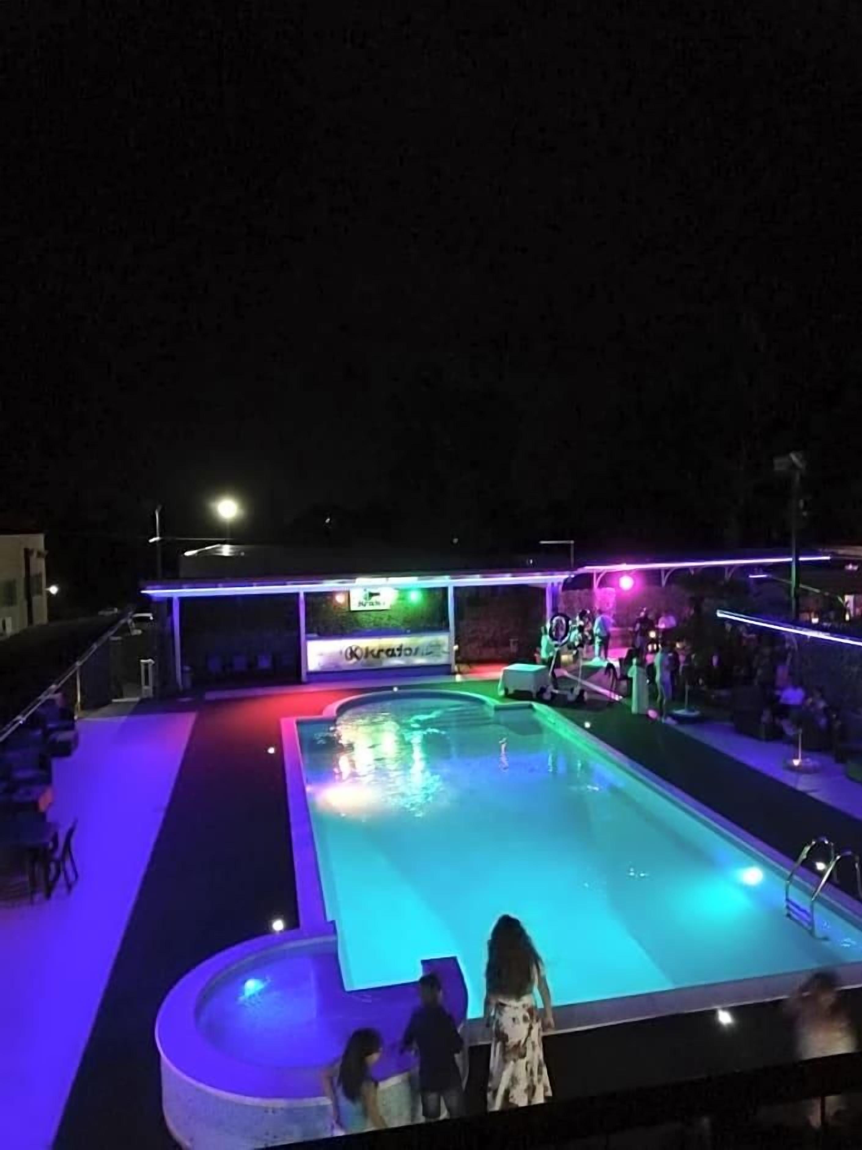 A swimming pool with a stage and seating area, surrounded by a covered deck.