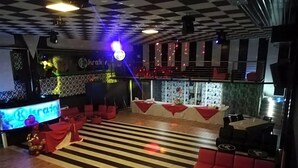 A bar area with a checkered floor, red seating, and a television screen. - Motel Kratos (Bisignano)