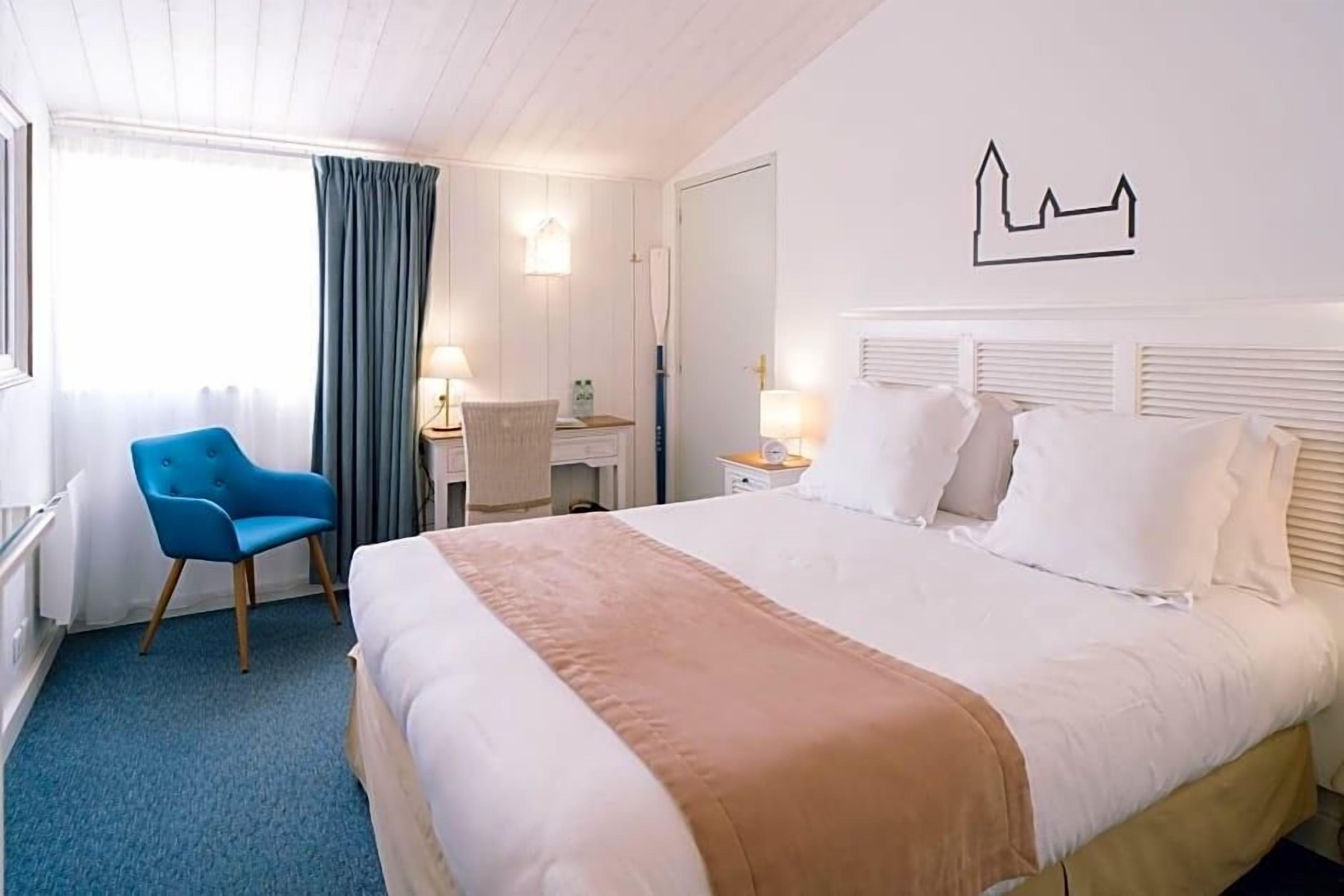 Une chambre d’hôtel comprenant un lit, une chaise, un bureau et une œuvre d’art accrochée au mur.