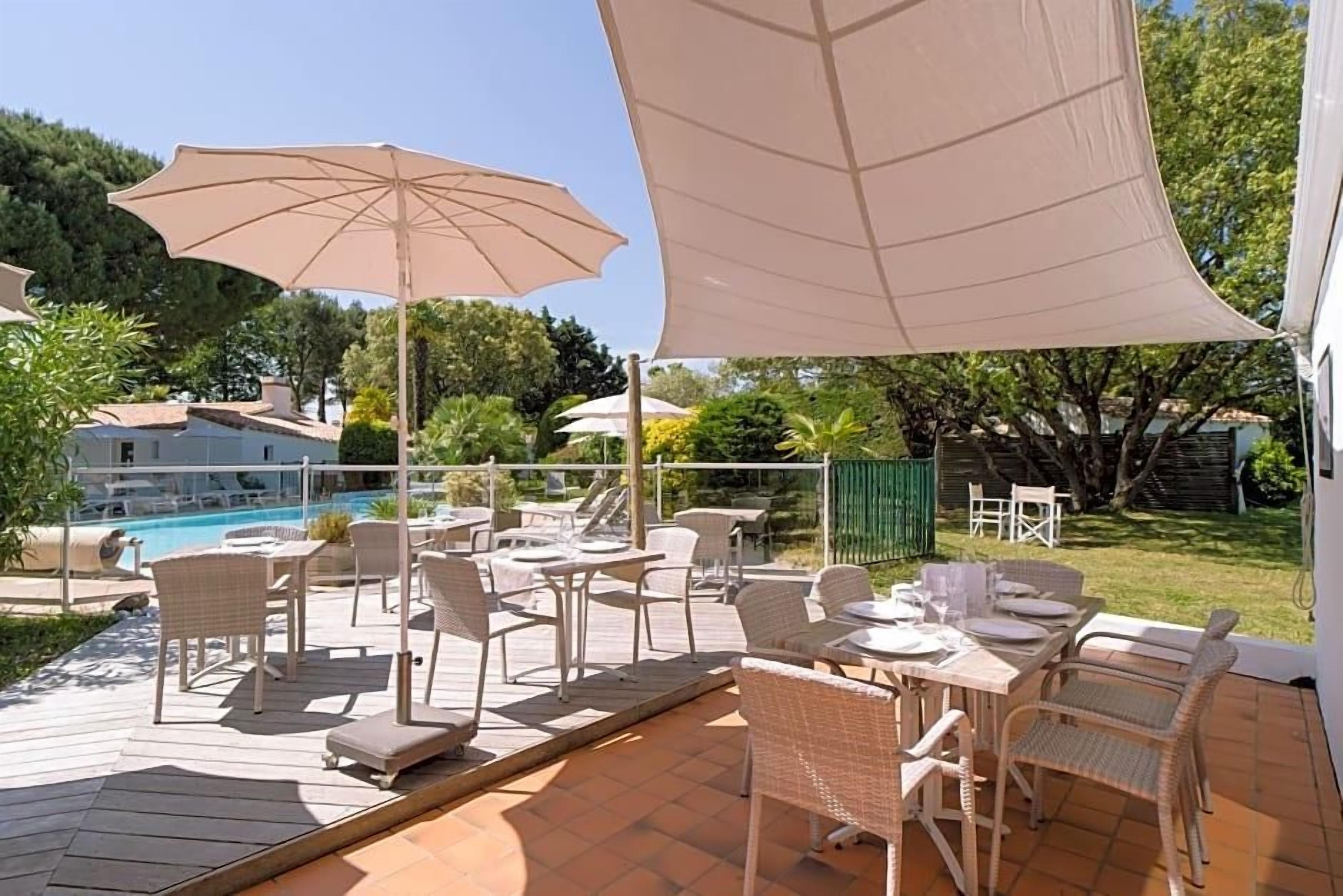 A patio area with outdoor seating, a pool, and a view of a residential building.