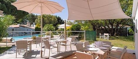 A patio area with outdoor seating, a pool, and a view of a residential building.
