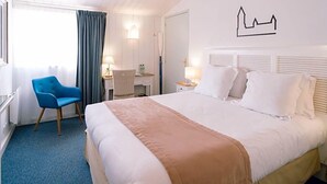 Une chambre d’hôtel comprenant un lit, une chaise, un bureau et une œuvre d’art accrochée au mur.