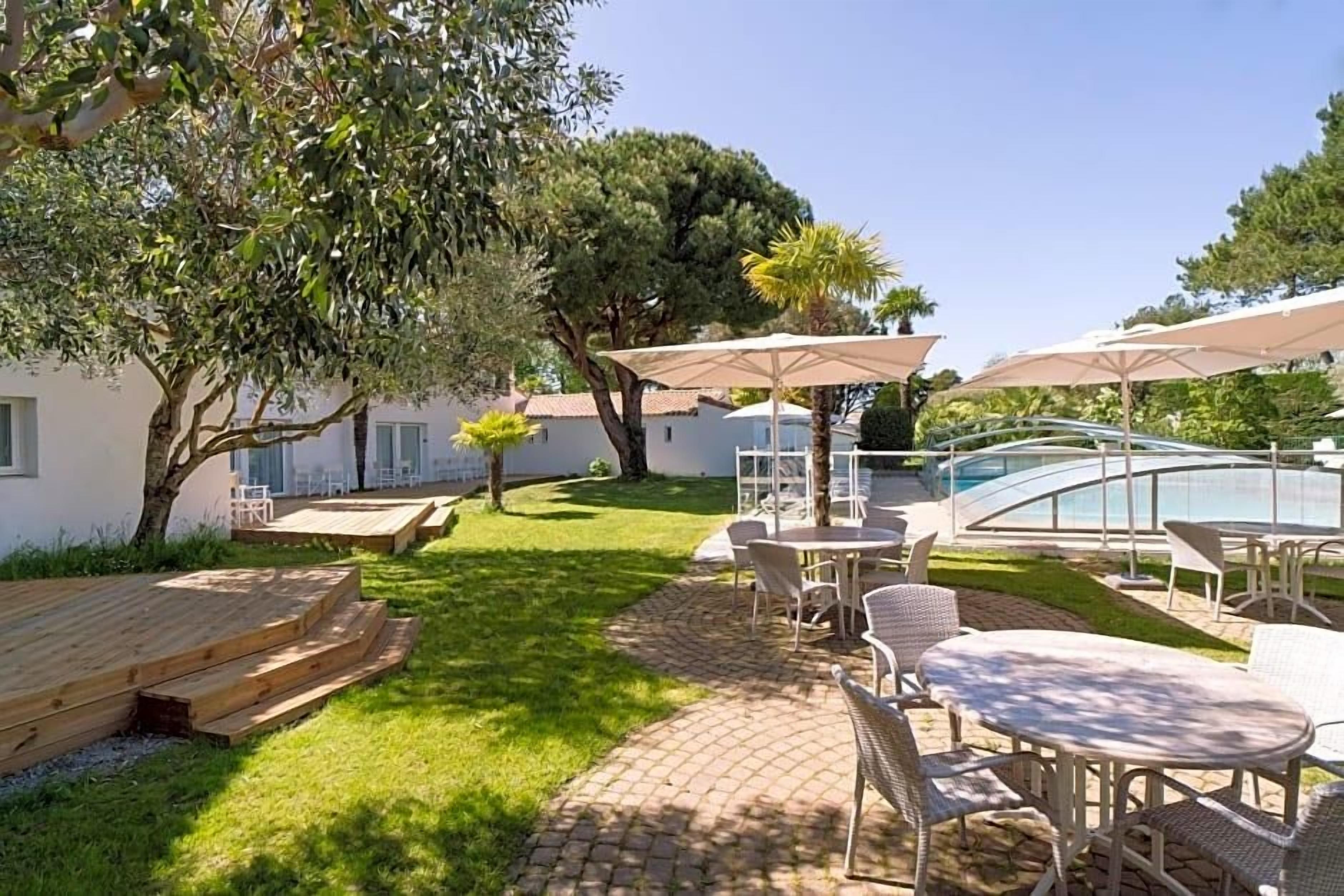 A patio area with outdoor seating, a pool, and a building in the background.