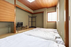 Ein Zimmer mit zwei Betten, einem Fernseher und einem Fenster.