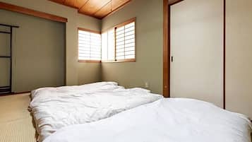 Una habitación con dos camas, un armario y una ventana con persianas de madera.