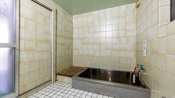 Un baño pequeño con azulejos, ducha, lavamanos e inodoro.