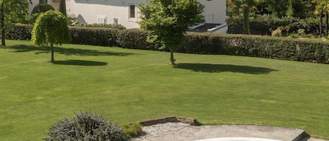 A residential property with a swimming pool, a well-maintained lawn, and a view of mountains in the background.