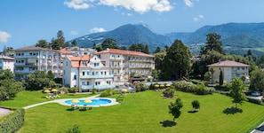 A hotel with multiple floors, a swimming pool, and a mountainous backdrop. - Hotel Filipinum (Merano)