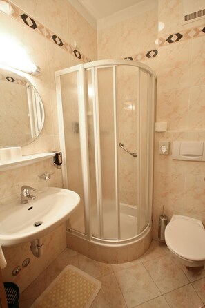 A bathroom with a shower enclosure, sink, toilet, and a mirror. - Hotel Filipinum (Merano)
